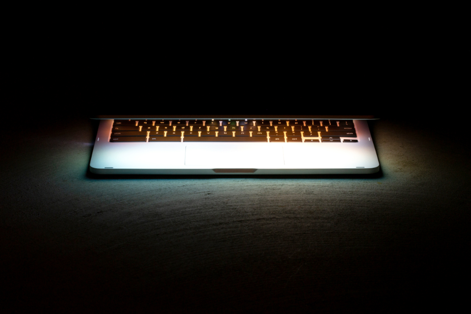 Laptop glowing in a dim workspace