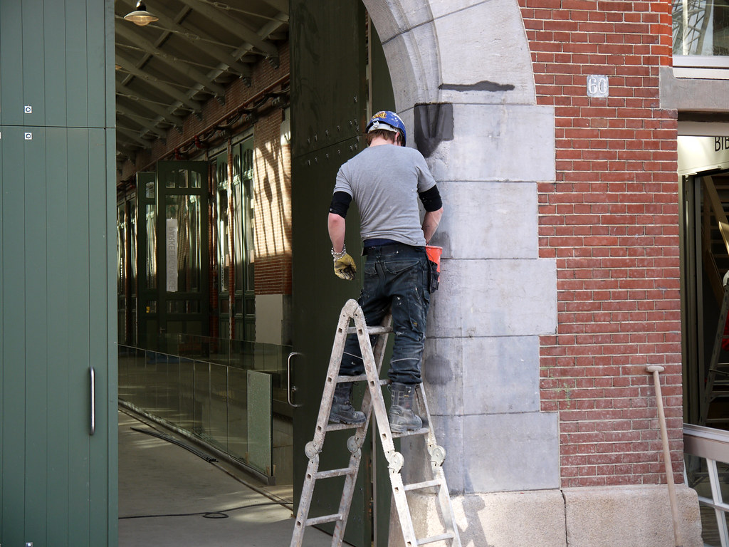 Contractor on a ladder at a storefront under renovation