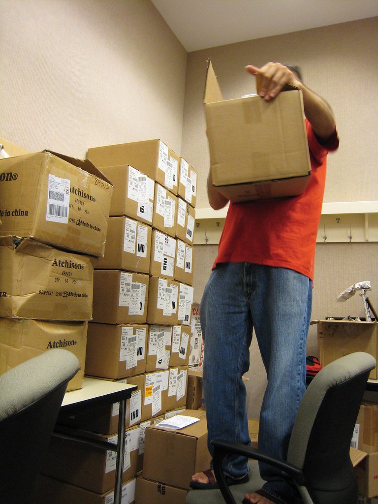 Worker stacking labeled moving boxes