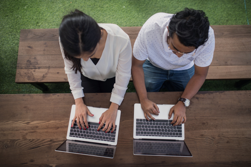 Coworkers collaborating with laptops, overhead view