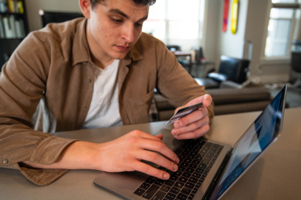 Person holding a credit card at a laptop