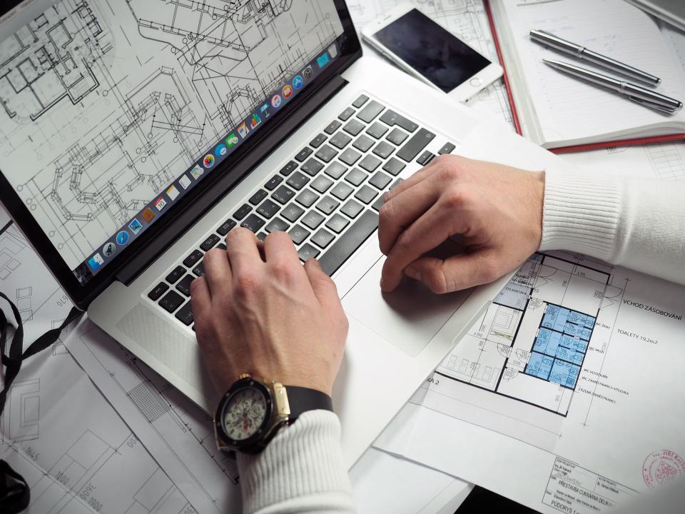 Designing on a laptop over layout plans