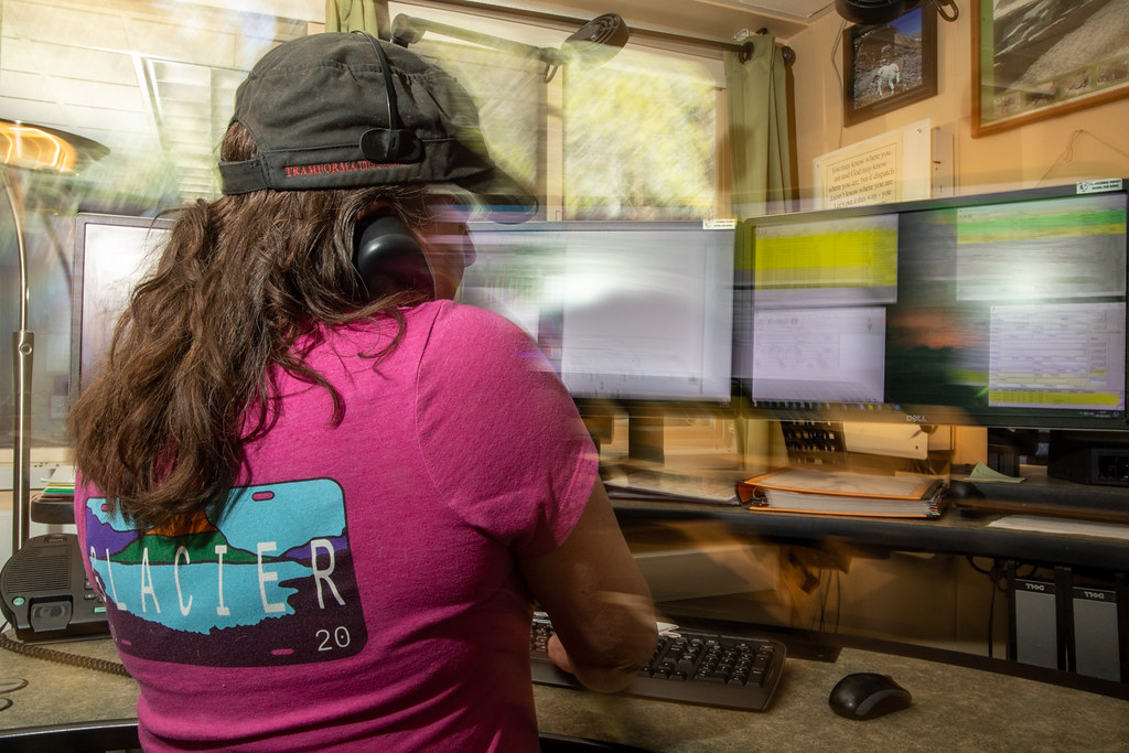Dispatcher taking a call at a desk of monitors