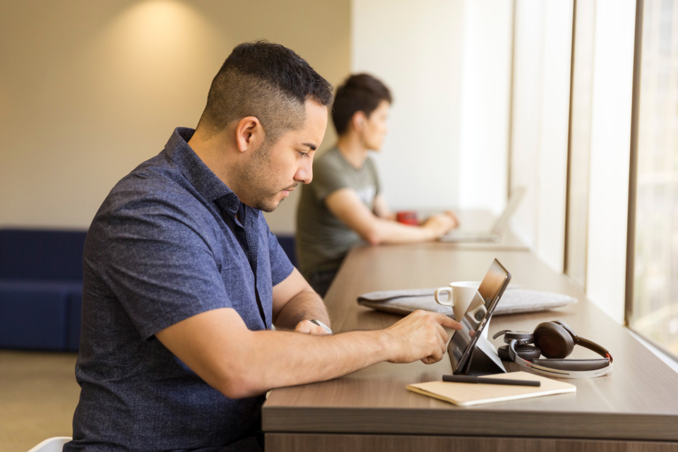 Person using a tablet and laptop at an office desk