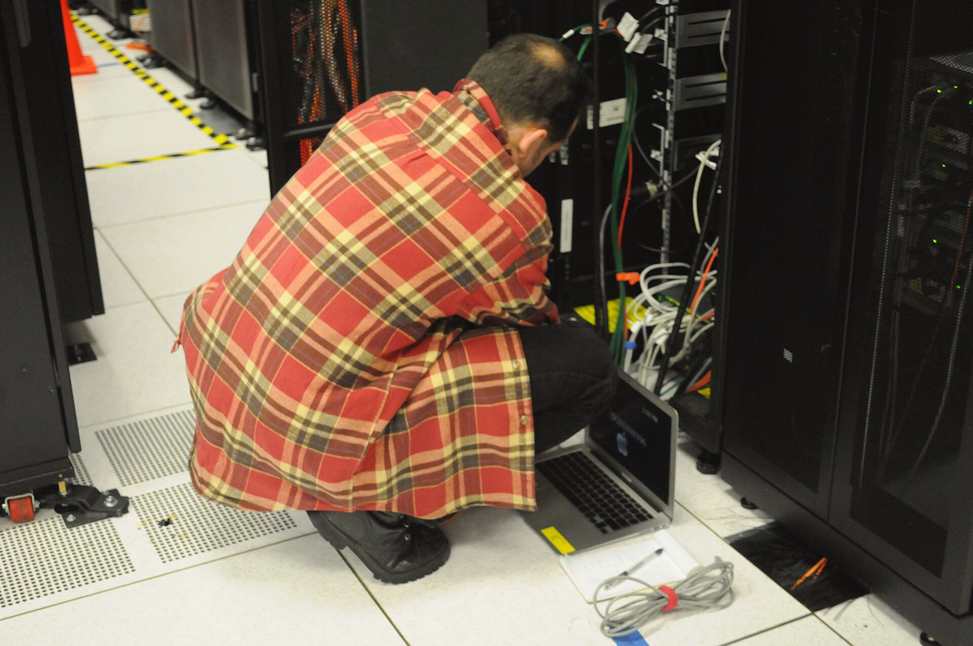 Technician with a laptop working on a server rack