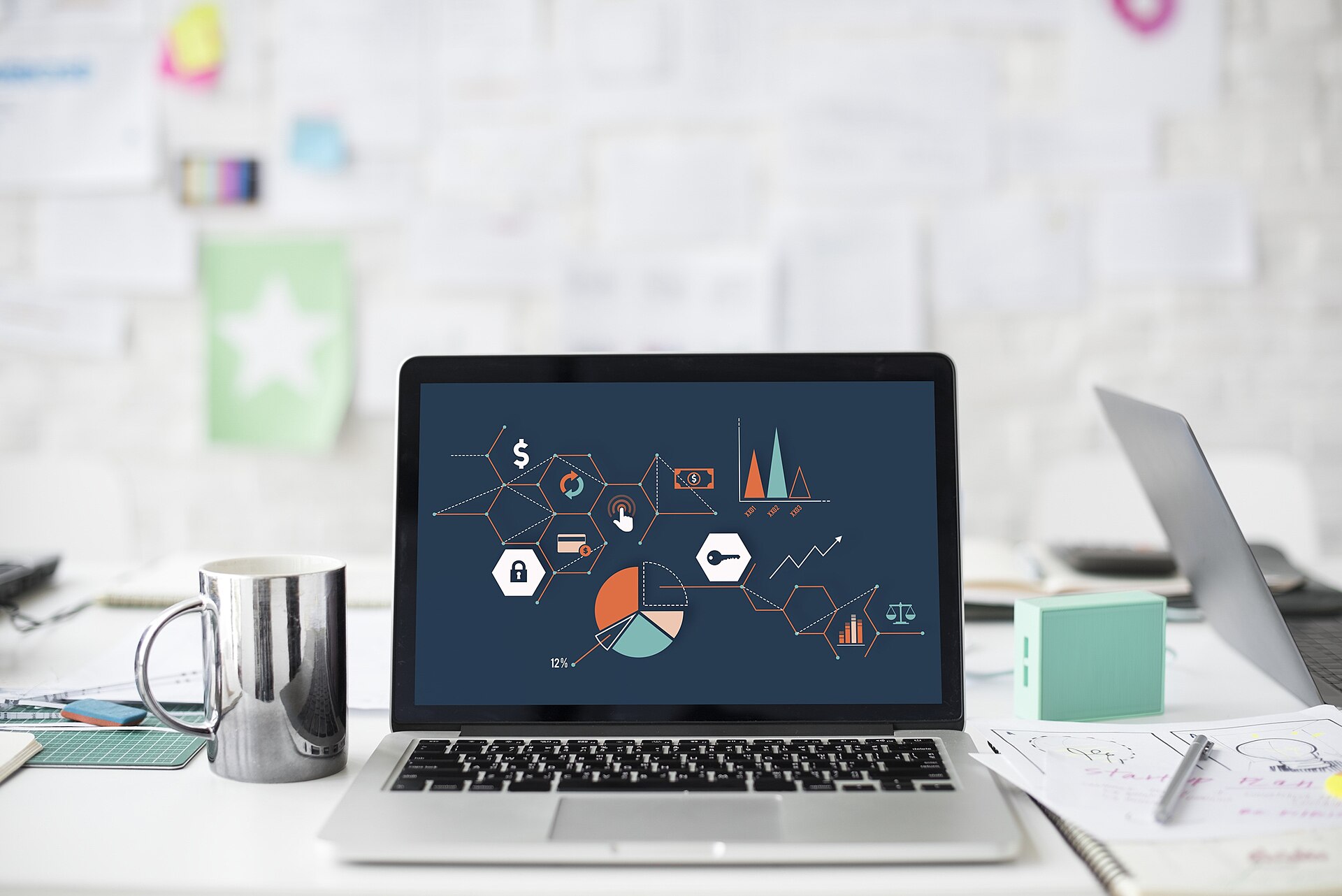 Laptop with many charts on screen on cluttered desk