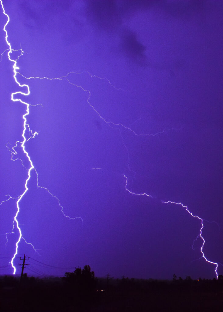 Lightning strike over power lines at dusk