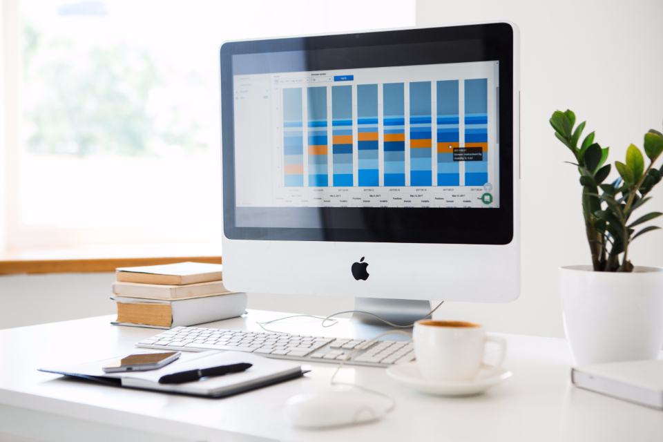 Desktop monitor showing a bar-chart analytics dashboard on a clean desk