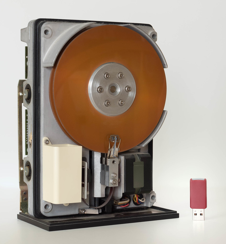Vintage hard drive next to a modern USB stick