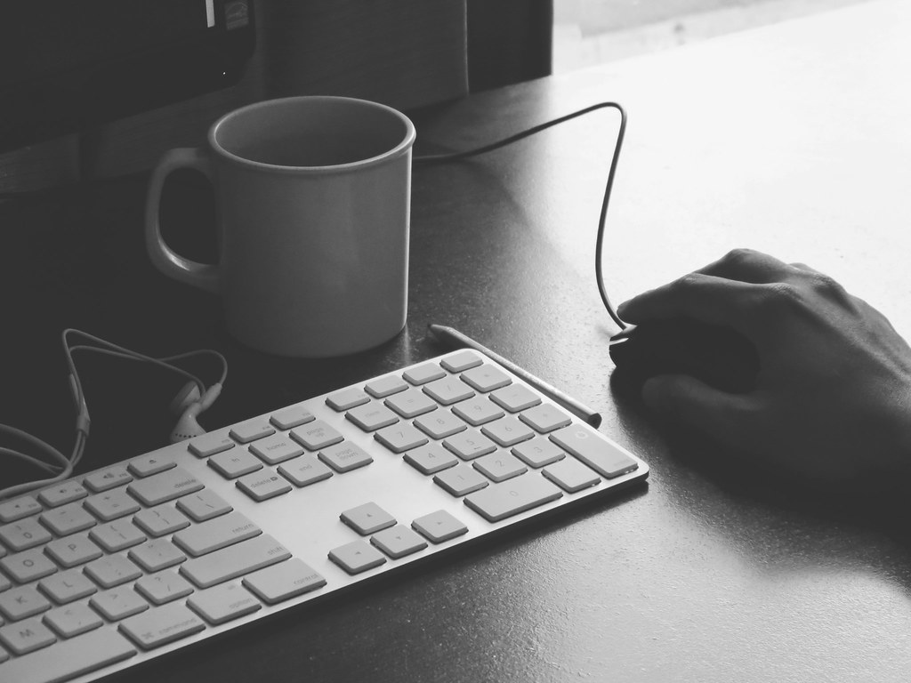A hand on a mouse beside a keyboard