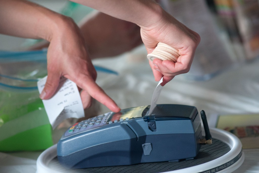 Hands printing a receipt at a modern point-of-sale card terminal
