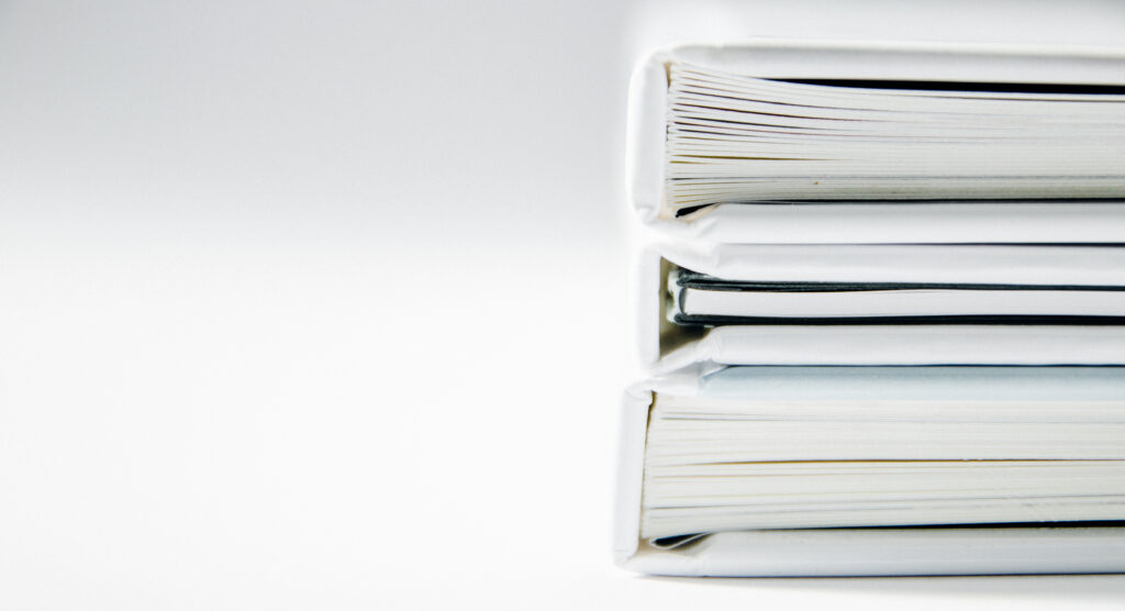 Thick binders of printed service records stacked on a desk